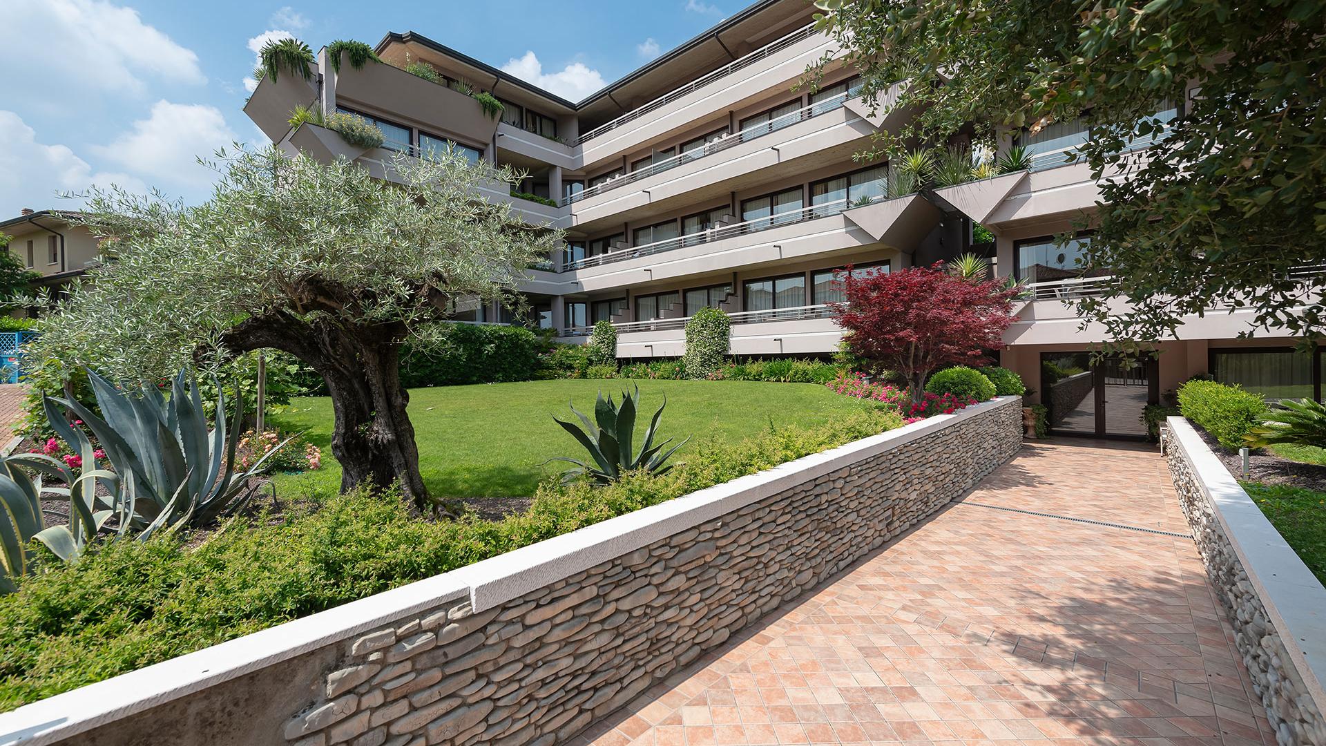 Moderno edificio residenziale con giardino curato e piante decorative.