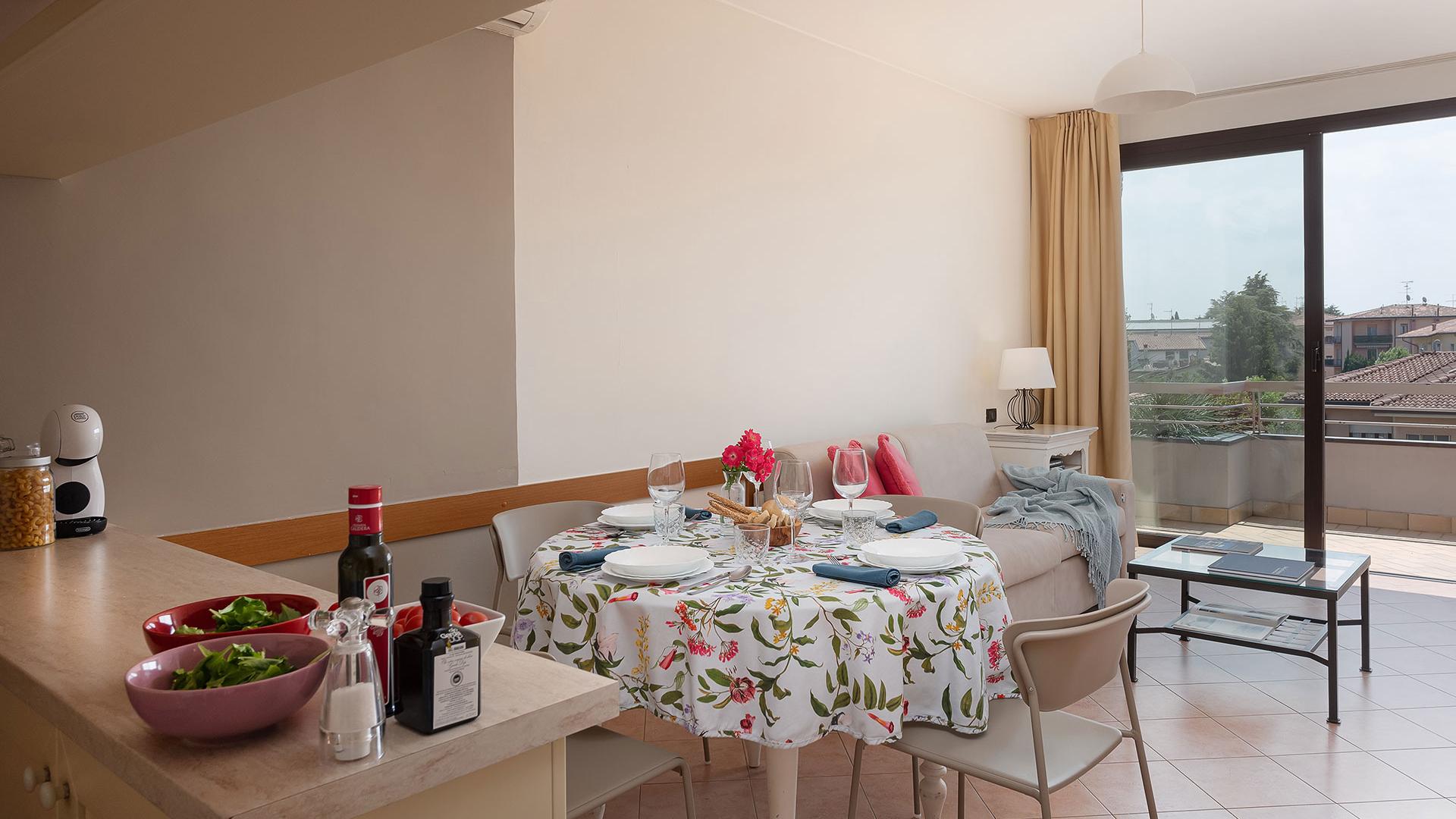 Bright kitchen with set table, living room, and balcony with a view.