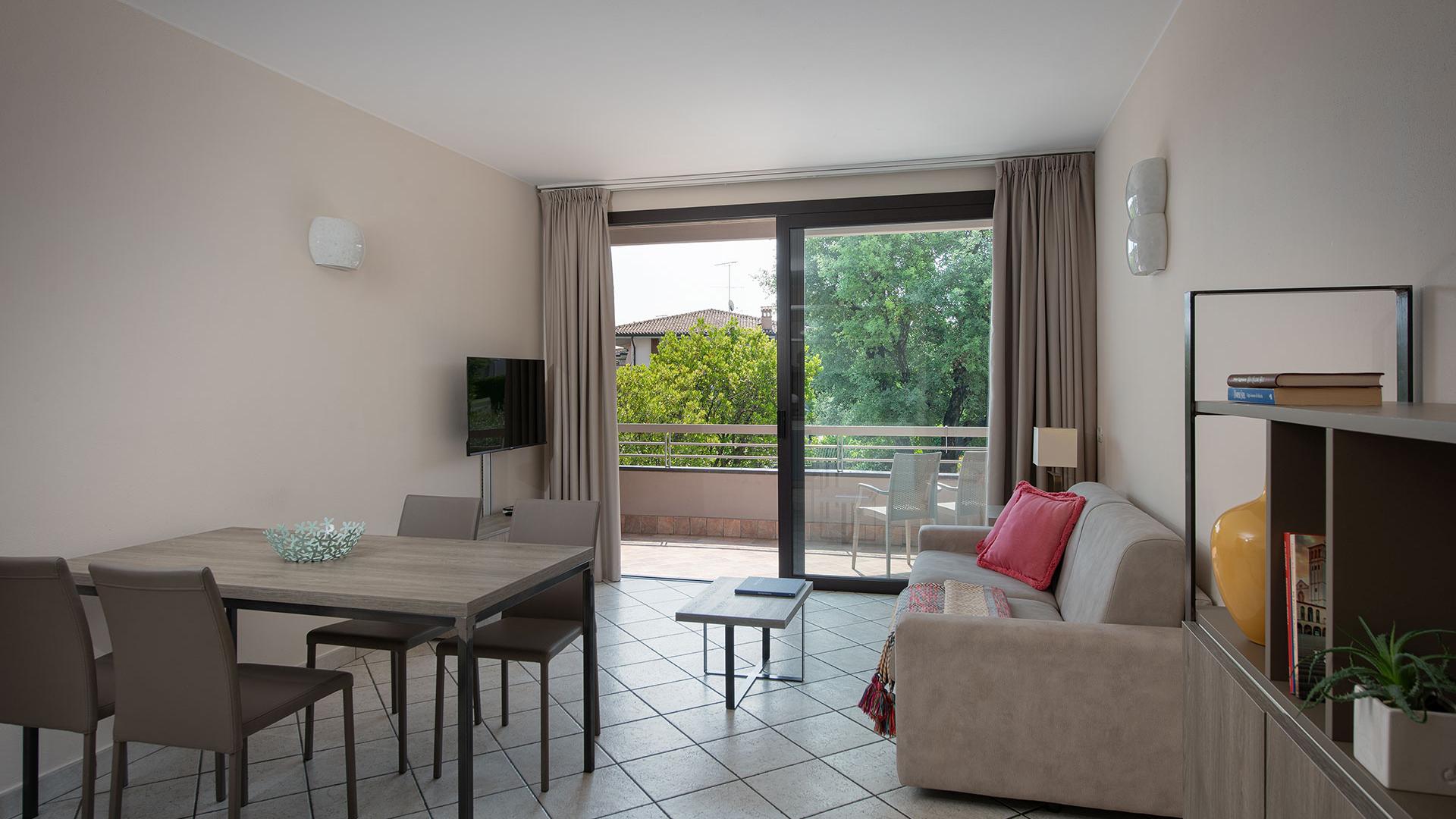 Modern living room with balcony, furnished with table, sofa, and TV.