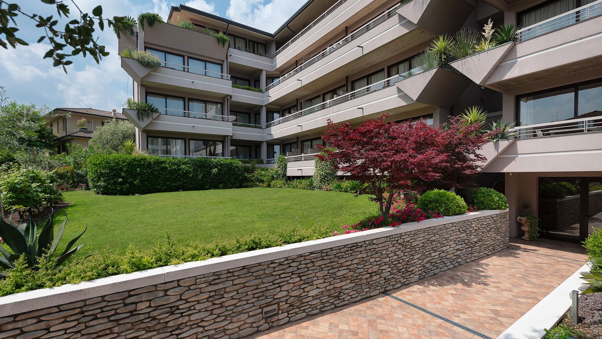 Moderno condominio con giardino curato e piante decorative su balconi.