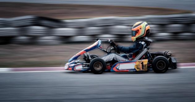 Kart racer on track, wearing yellow helmet and racing suit.