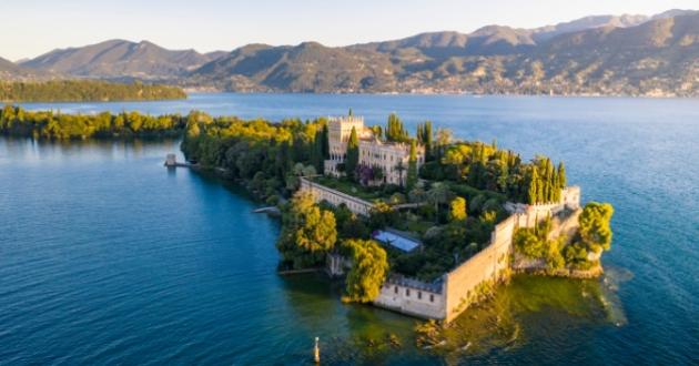 Island with castle surrounded by lake and mountains, picturesque landscape.