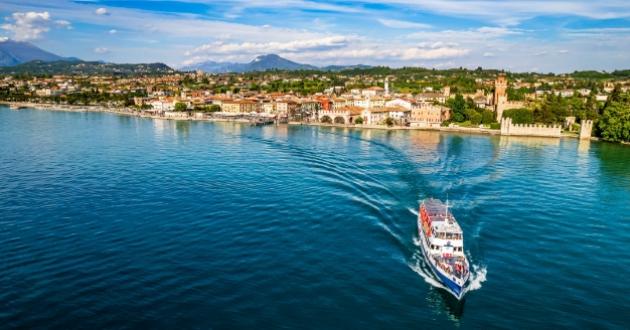 Boat sailing towards a picturesque coastal town with mountains in the background.