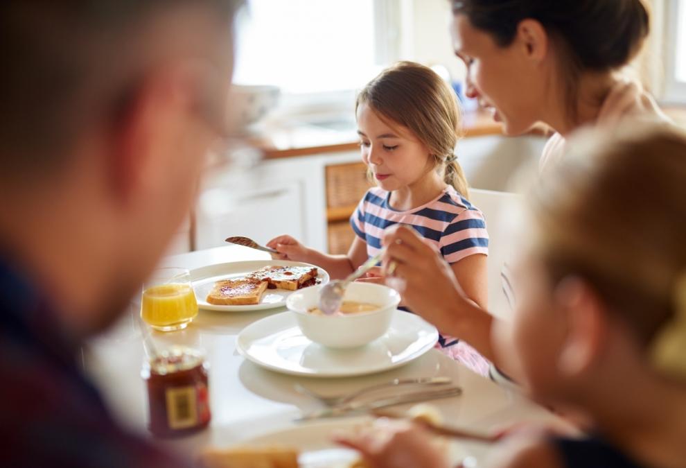 Famiglia che fa colazione insieme con pane tostato e succo d'arancia.