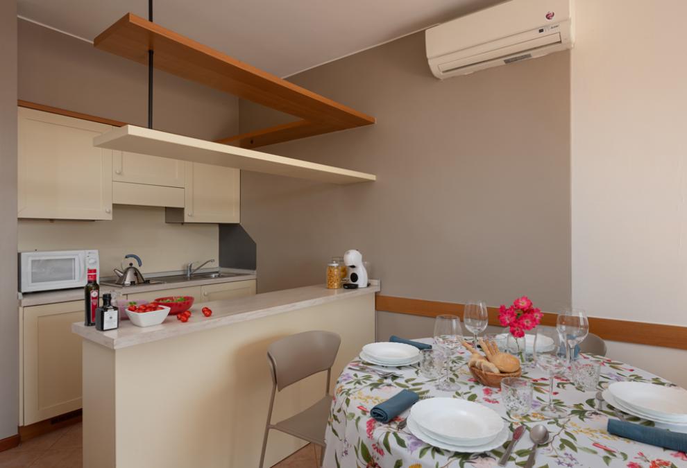 Modern kitchen with dining table, air conditioning, and floral decoration.