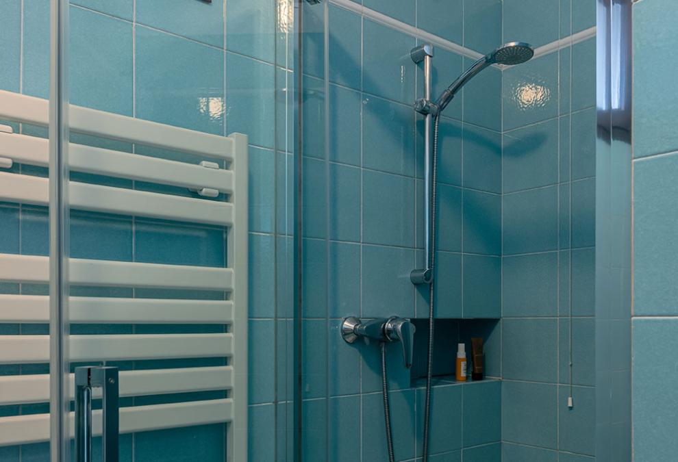 Small bathroom with modern shower and blue tiles.