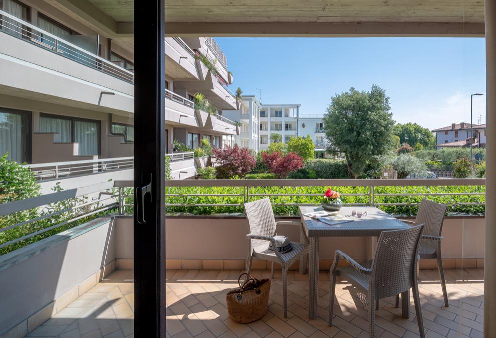 Terrace with table and chairs, view of garden and modern buildings.