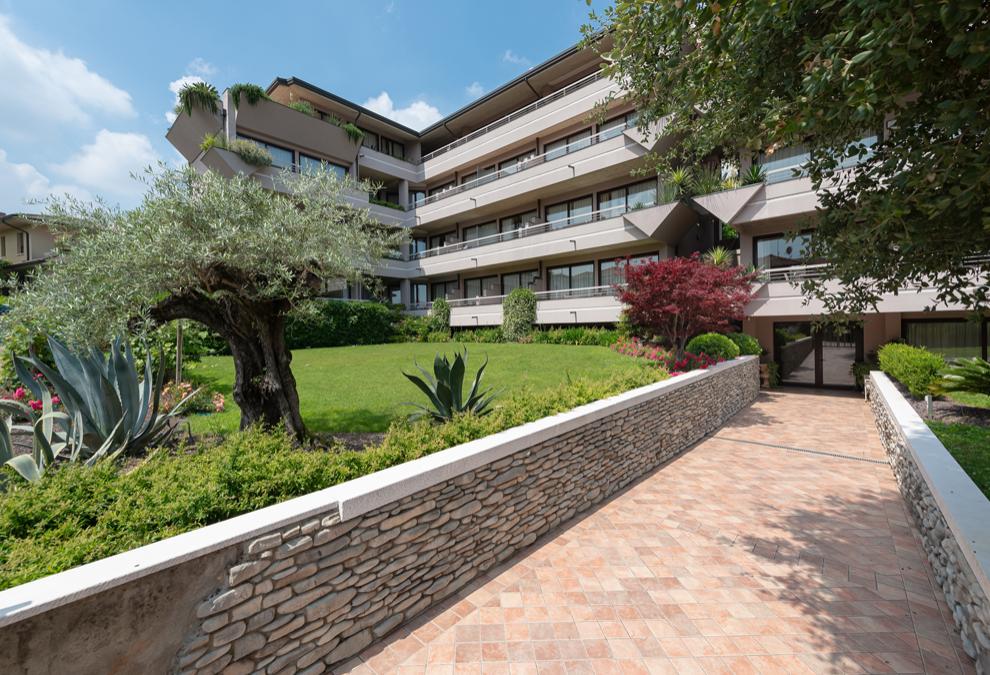 Edificio moderno con terrazze verdi e giardino curato.