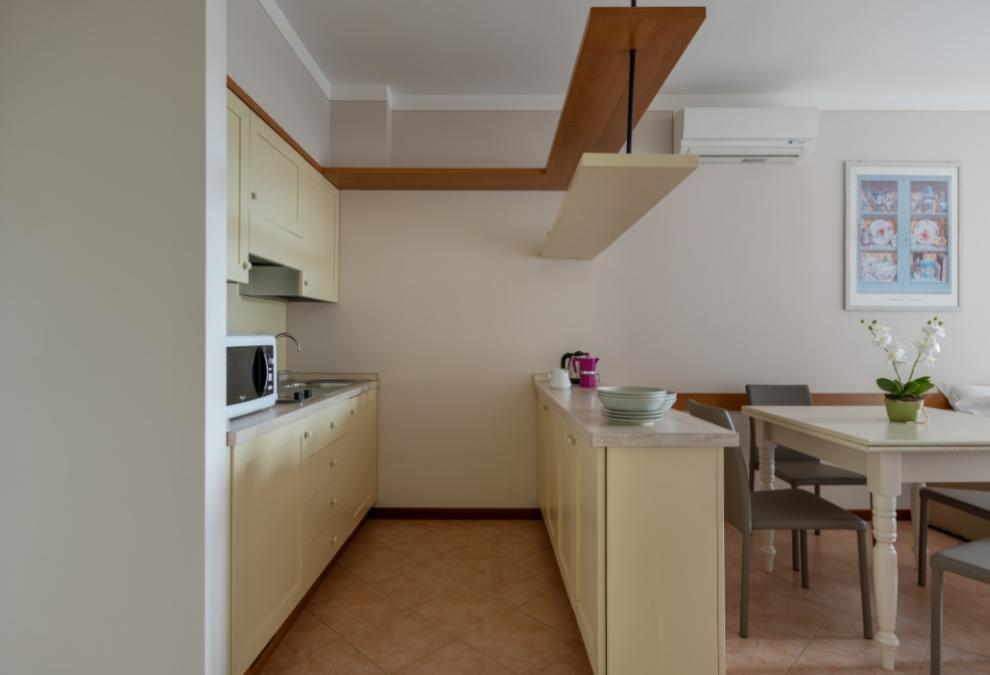 Modern kitchen with light furniture, dining table, and wall decorations.