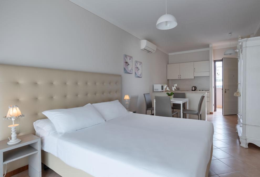 Bright room with double bed and kitchenette, elegant decorations.