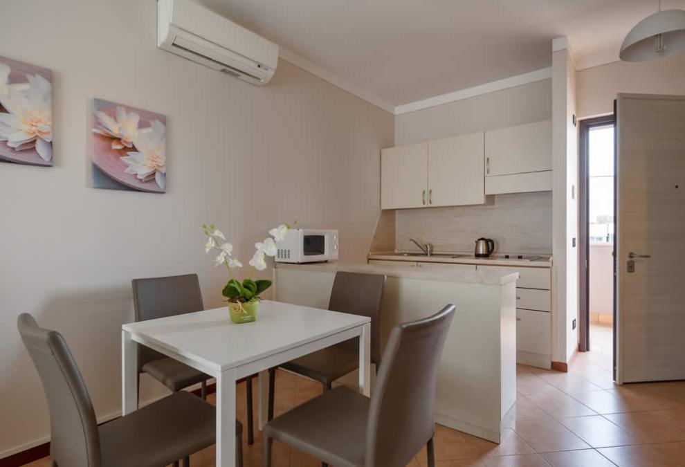 Modern kitchen with dining table, air conditioning, and floral decorations.