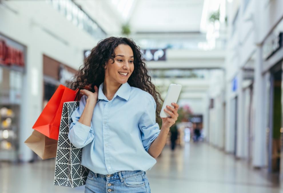 Woman with shopping bags and smartphone in a mall.