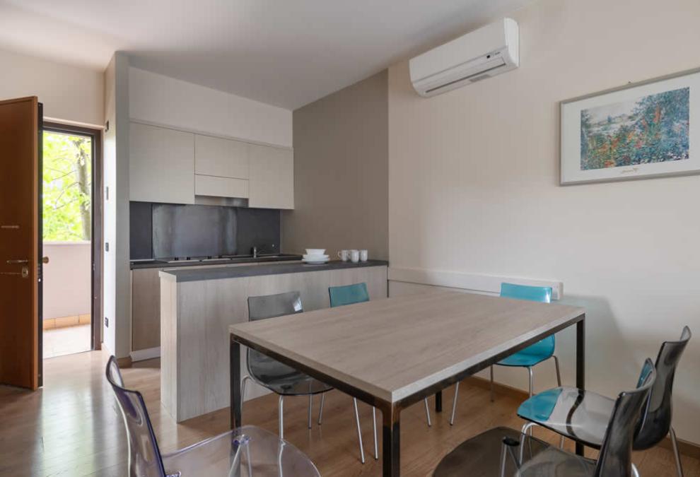 Modern apartment with open kitchen, dining table, and air conditioning.