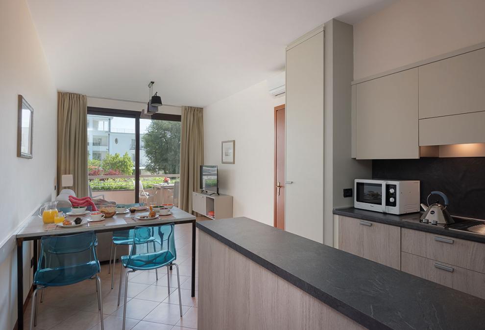 Modern apartment with kitchen, dining table, and garden view.