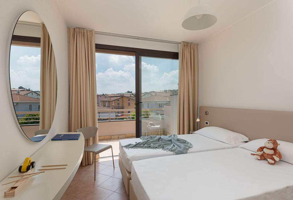 Bright room with single beds and balcony view.