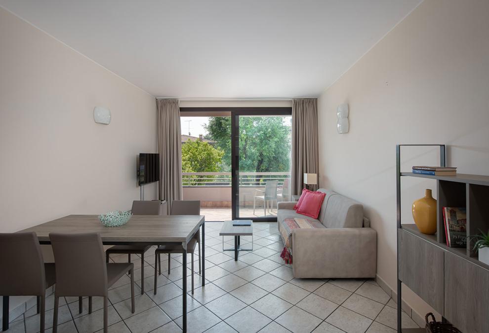 Modern living room with balcony, TV, sofa, and dining table.