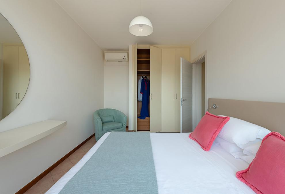 Modern bedroom with double bed and open wardrobe.