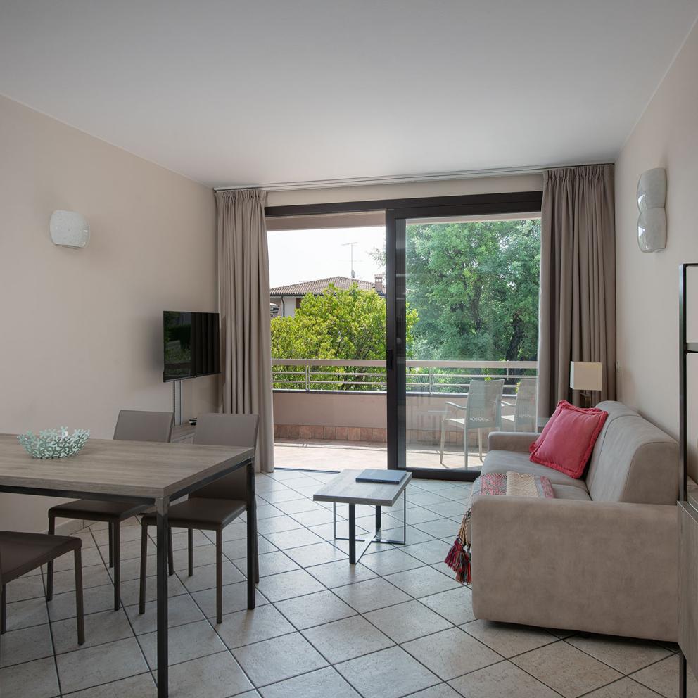 Modern living room with balcony, furnished with table, sofa, and TV.